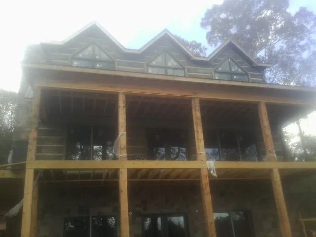 Dormers and porch framing on a large log home under construction — Roof Coating work by our crew in Wataga
