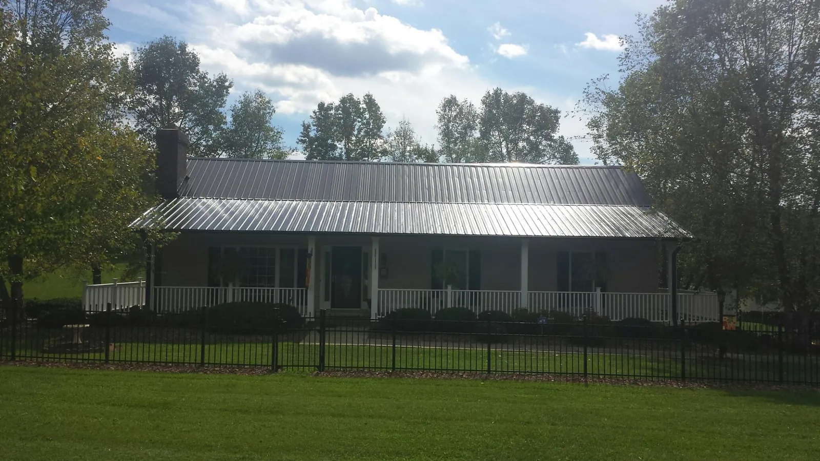 Gray metal roof on a brick ranch with a full width front porch — Gutter Guard Installation work by our crew in Wataga