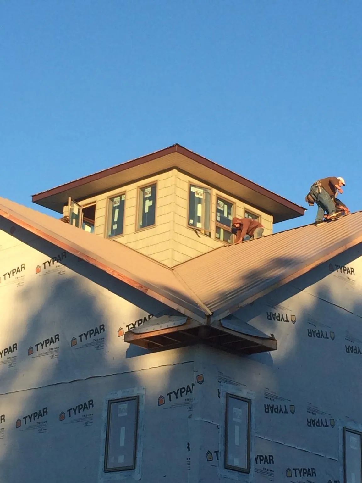 Roofers working around a rooftop cupola on a new metal roof at sunset — Roof Waterproofing in Wataga by Roofing Brothers